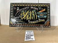 Front view of Butterfly Brand porcelain enamel sign showing artwork and text clearly with stand and small lot card visible.