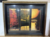 Framed and matted triptych print of fall scenery with gold, red, orange colors in vertical panels.