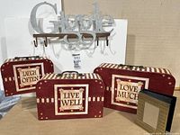 Three decorated suitcase style boxes with motivational sayings on front and metal 'Giggle' hanging rack behind.