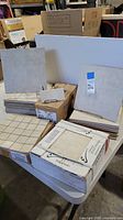 Photo showing boxes and stacks of various tiles including Paradiso floor tiles and Renaissance Crema floor tiles sheets arranged on a table.