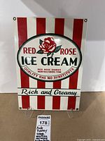Front view of the porcelain enameled sign featuring Red Rose Ice Cream with red and white stripes and brass grommets.