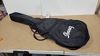 Front side of the soft sided Ibanez guitar case showing the white logo and zippered pocket.
