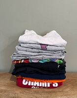 Stack of eight folded women’s t-shirts showing various colors and graphics