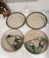 Top view of four plates: two floral, two speckled with green rim