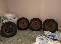 Four tires with rims leaning against wall