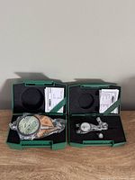 Both indicators in open green cases with paperwork visible