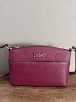 Front view of burgundy Kate Spade leather crossbody with logo plate