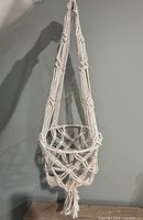 Full view of macrame plant hanger hanging against wall