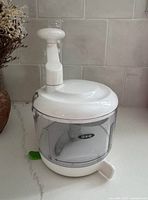 Front view of OXO manual food processor showing handle and clear bowl