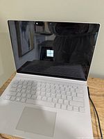 Laptop open, powered on, Windows boot logo visible.