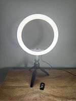 Front view of illuminated ring light mounted on mini tripod with remote in foreground