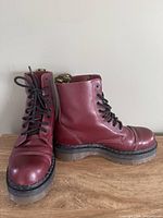 Pair of cherry red Dr. Martens Crazy Bomb boots angled, showing platform soles and lacing