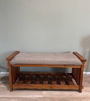 Front view of wood bench showing padded seat and lower slatted shelf