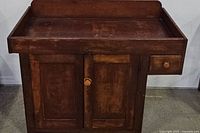 Front view of wooden dry sink cabinet showing one drawer on the right side, two doors under the drawer, and raised back and side edges on top tray area.