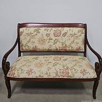Front view showing the mahogany frame and floral patterned upholstery on the backrest and seat.