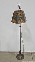 Full view of the floor lamp showing the stained glass style lampshade and decorative base.