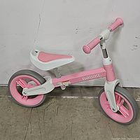 Side view of pink Bobike toddler balance bike showing frame, wheels, seat, and handlebars.