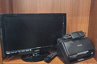 VIZIO TV, Epson scanner, remote, and power adapter visible on a wooden shelf.