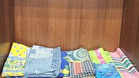 Folded assorted fabric pieces showing varied patterns and colors including yellow and blue floral, paisley, and striped designs.