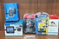 Photo showing all items of the lot including the rain station, transfer pack, power pack, Canon ink, and headphones arranged side by side on a wooden surface.