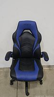 Front view of the Staples Emerge Vortex gaming chair showcasing the black and blue bonded leather upholstery and ergonomic design, including the 'Vortex' embossed headrest.