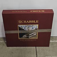 Maroon Scrabble Giant Deluxe Edition box showing the game's branding and image of the board and tiles, sealed with tape.