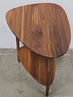 Front three-quarter view showing triangular top, lower shelf, and three round legs