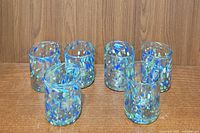 Six confetti styled drinking glasses arranged on a wooden surface in two rows, clearly showing their colorful dot pattern and cylindrical shape