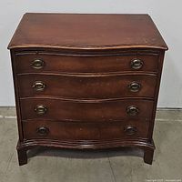 Front view of the 4-drawer Mahoney chest showing brass handles and curved drawer fronts.