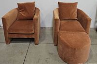 Front view of two rust velvet upholstered accent chairs and ottoman