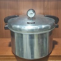 Front view of the Presto pressure cooker canner with visible pressure gauge and dual handles.