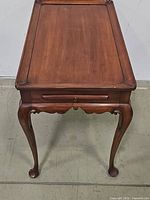 Front view of a Queen Anne style wooden tea table showing curved legs and a rectangular tabletop.