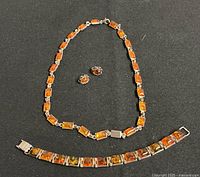 Necklace, bracelet and earrings laid flat on black background