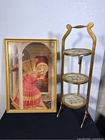 Framed Usus Antiquior religious print alongside 3-tier folding cake stand.
