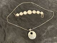 Photo showing both the mother of pearl bracelet and the silver chain necklace with large circular pendant.