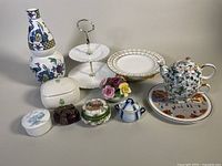 Full display showing assortment of porcelain and bone china items including double-tier tray, vases, teapot, trinket boxes, and decorative flowers