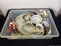 Bin filled with assorted chinaware including teacups, saucers, plates, and figurines from above.