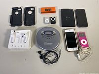 Overview of all electronic devices including Apple iPods, iPhones, Sony CD Walkman and earphones laid on table.