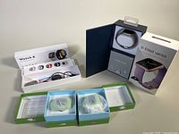 Fitbit Versa Special Edition smartwatch in its box, Fitbit Watch 6 with charger and warranty card, and two kids smartwatches in open boxes