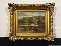 Full view of the framed oil painting depicting lush landscape and river.