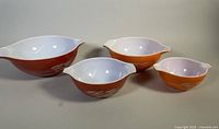 Four Pyrex mixing bowls in the Autumn Harvest pattern displayed from front, showing size difference and two-tone color.