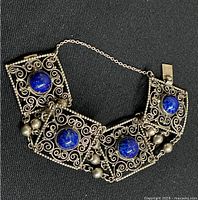 Full view of the sterling silver bracelet showing four square links each with a central lapis lazuli stone, connected by small rings and attached safety chain present.