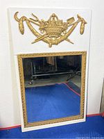 Front view of the vintage Borghese embossed wall mirror on a white painted wood board with gold embossed decorations and rectangular mirror.