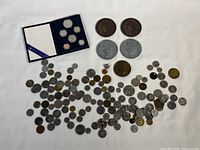 Overview of entire coin and medallion lot showing the 1982 Canadian Mint Set box open with coins displayed and a large assortment of other coins spread below.