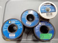 Four spools of wire arranged on a plastic surface, shows labels and wire ends visible