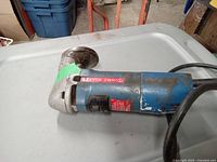 Side view of Bosch Scintilla electric nibbler showing worn blue body and silver cutting head with circular attachment.