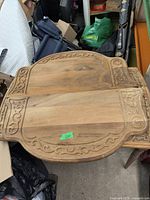 Top view of the wooden drop leaf table showing carved scrollwork decoration on the detached drop leaf sides and central table top.