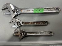 Photo of three used adjustable wrenches of different sizes and brands showing surface wear and rust on some tools.