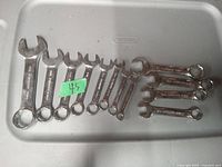 Lot of 12 small combination wrenches in both metric and SAE sizes placed in a plastic container.