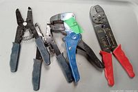 Photo showing four wire strippers with varying handle colors and designs on a white tray